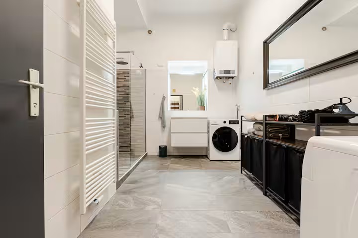 Badezimmer mit Waschtisch, Dusche, Handtuchheizkörper und Waschmaschine
