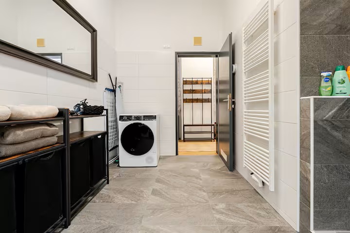 Blick durch das Badezimmer zur Tür mit Waschmaschine und Ablageflächen