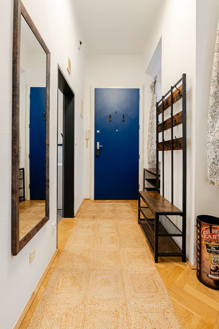 Heller Vorraum mit blauer Wohnungstür, Garderobe und Spiegel